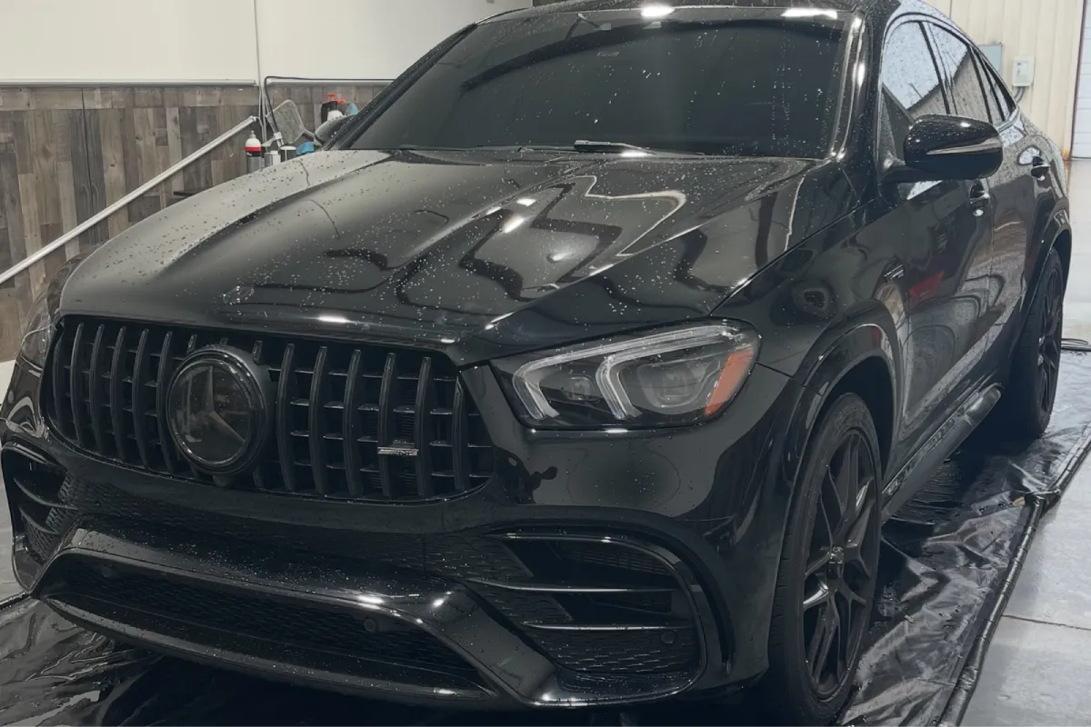 Black BMW Alpina SUV parked inside auto detailing garage.